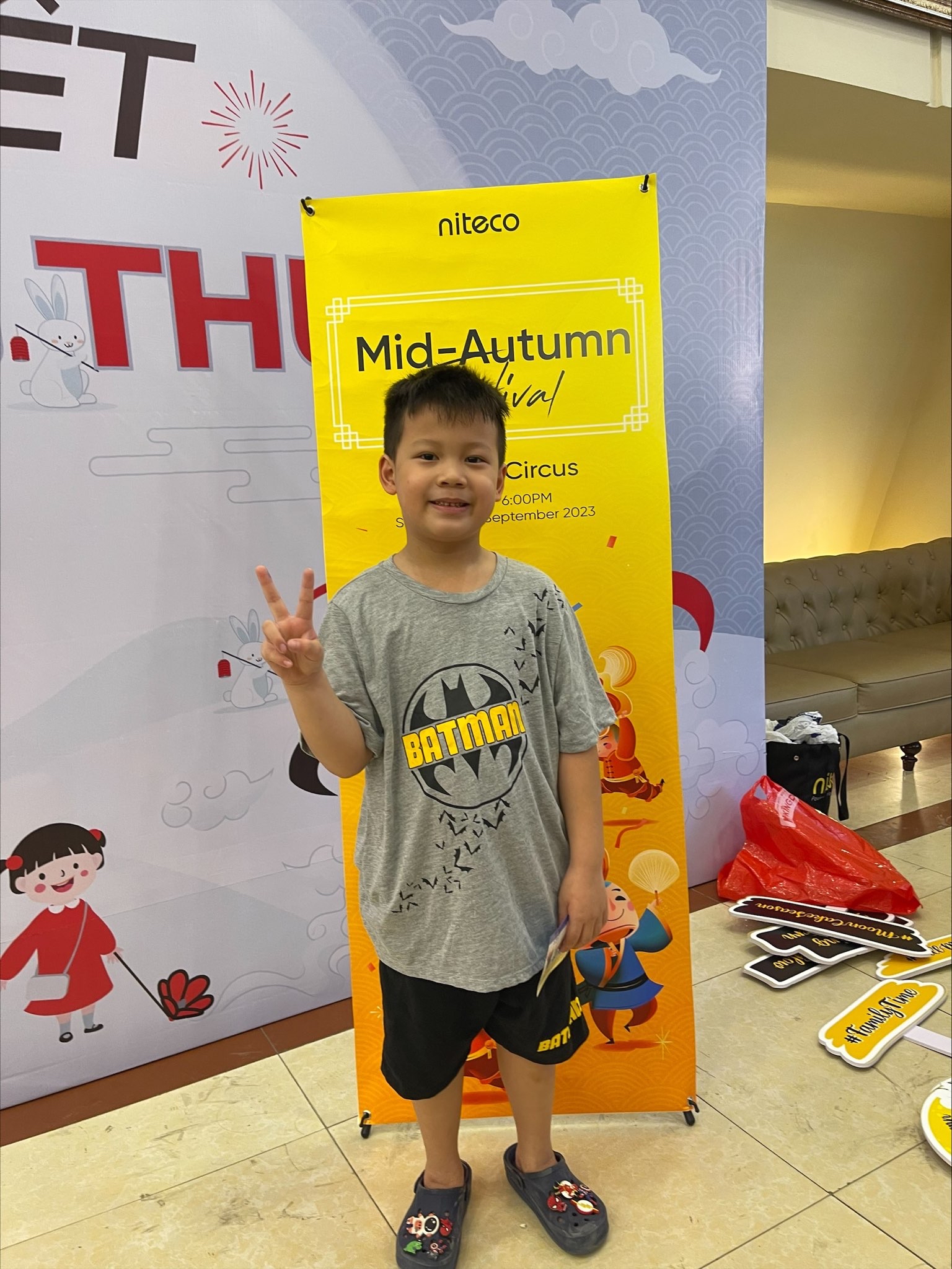 Boy wearing Batman shirt posing with peace sign at Mid-Autumn Festival event