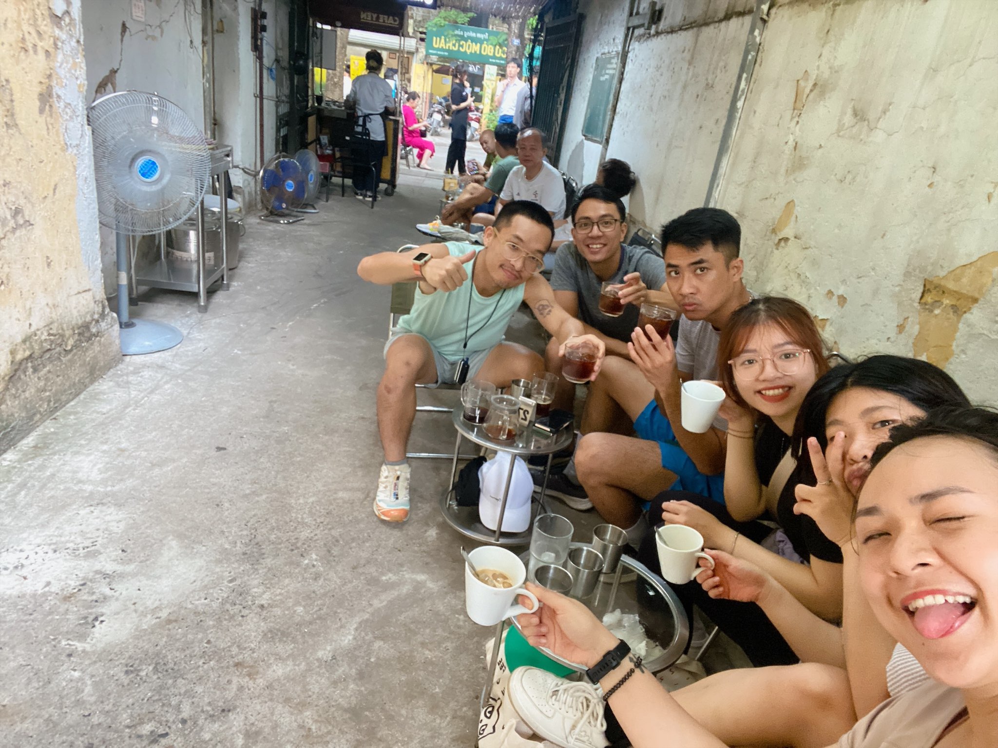 Friends enjoying traditional Vietnamese coffee at a narrow Hanoi café alley