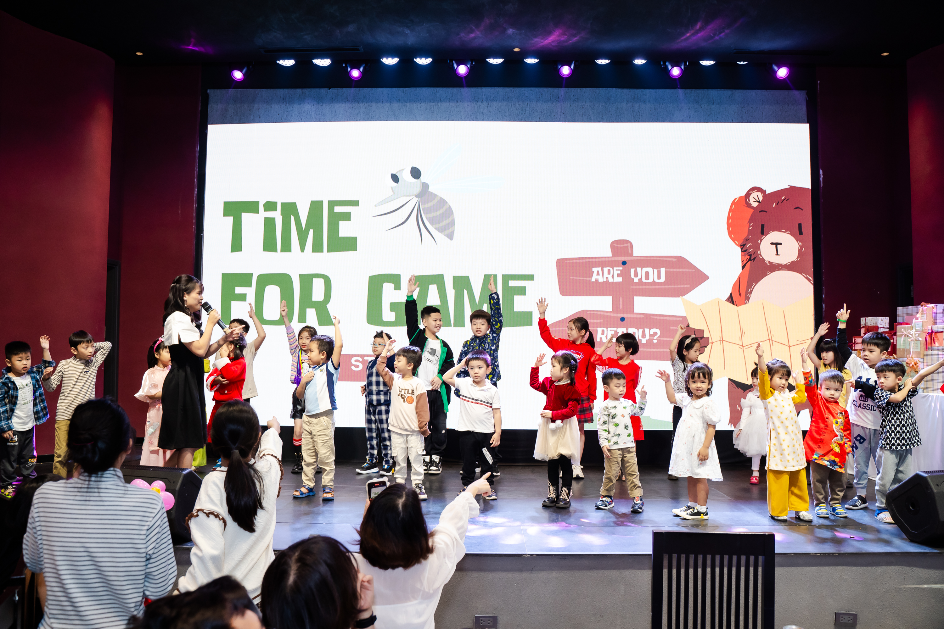 Kids participating in interactive classroom games with teacher on stage