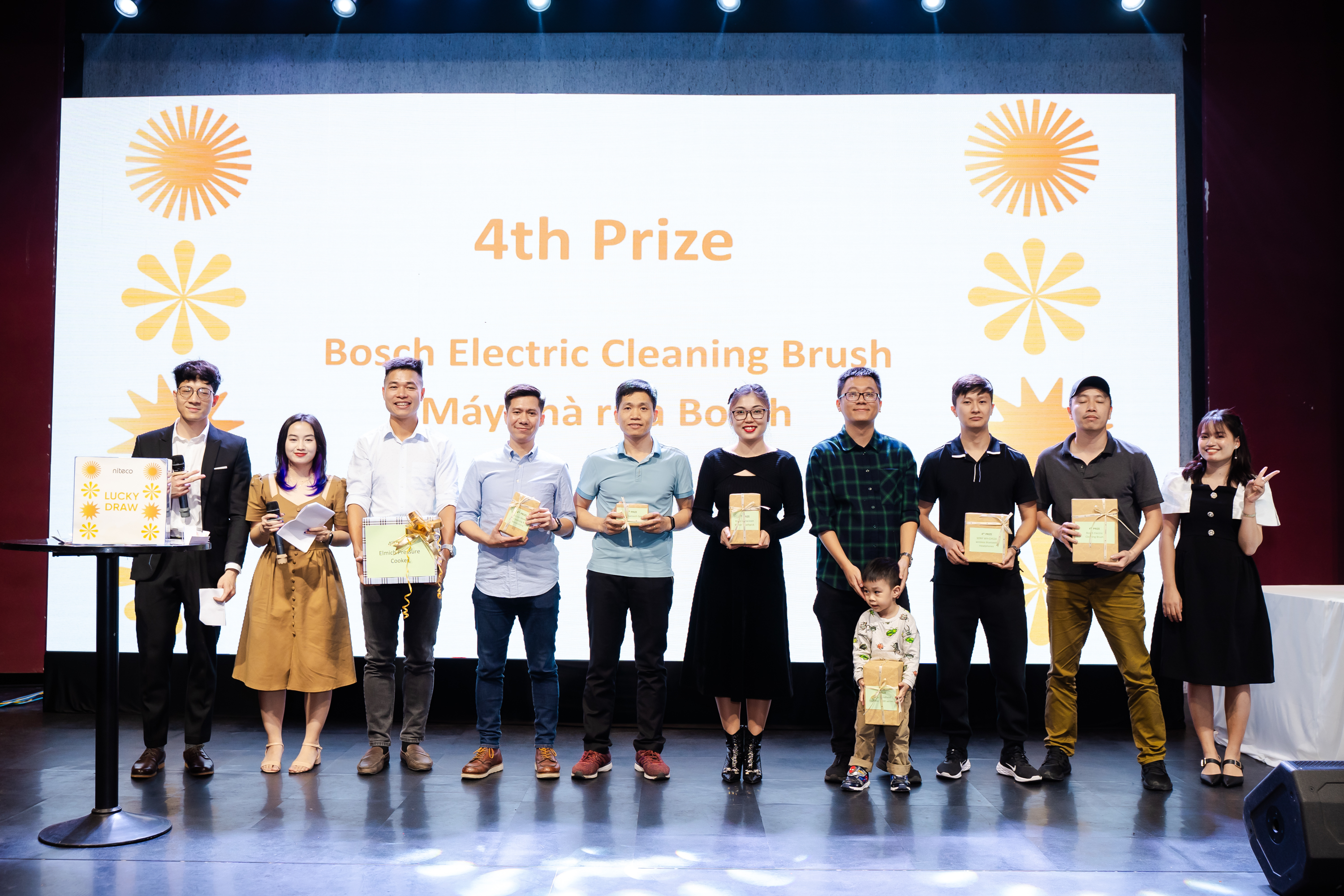 Winners holding Bosch Electric Cleaning Brush prizes on stage during lucky draw event