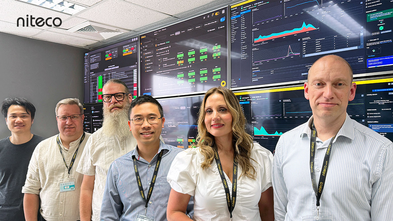 Niteco team standing in front of data monitoring screens showing analytics and metrics