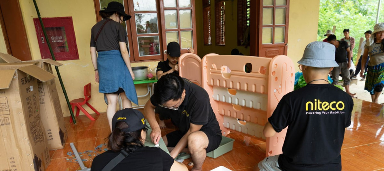 Volunteers assembling plastic playground equipment in a community building