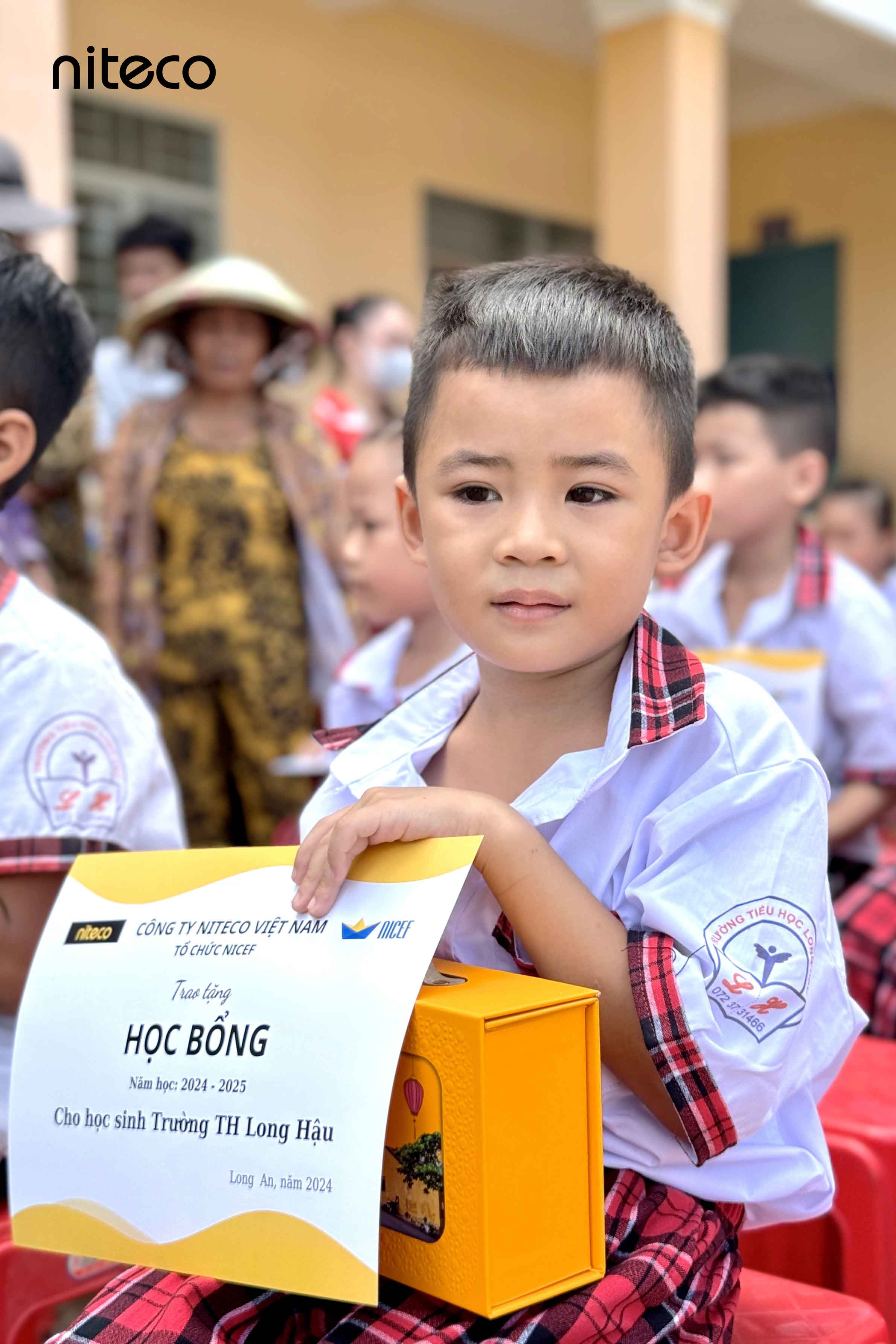 Young student from Trường TH Long Hậu holding Niteco scholarship certificate 2024
