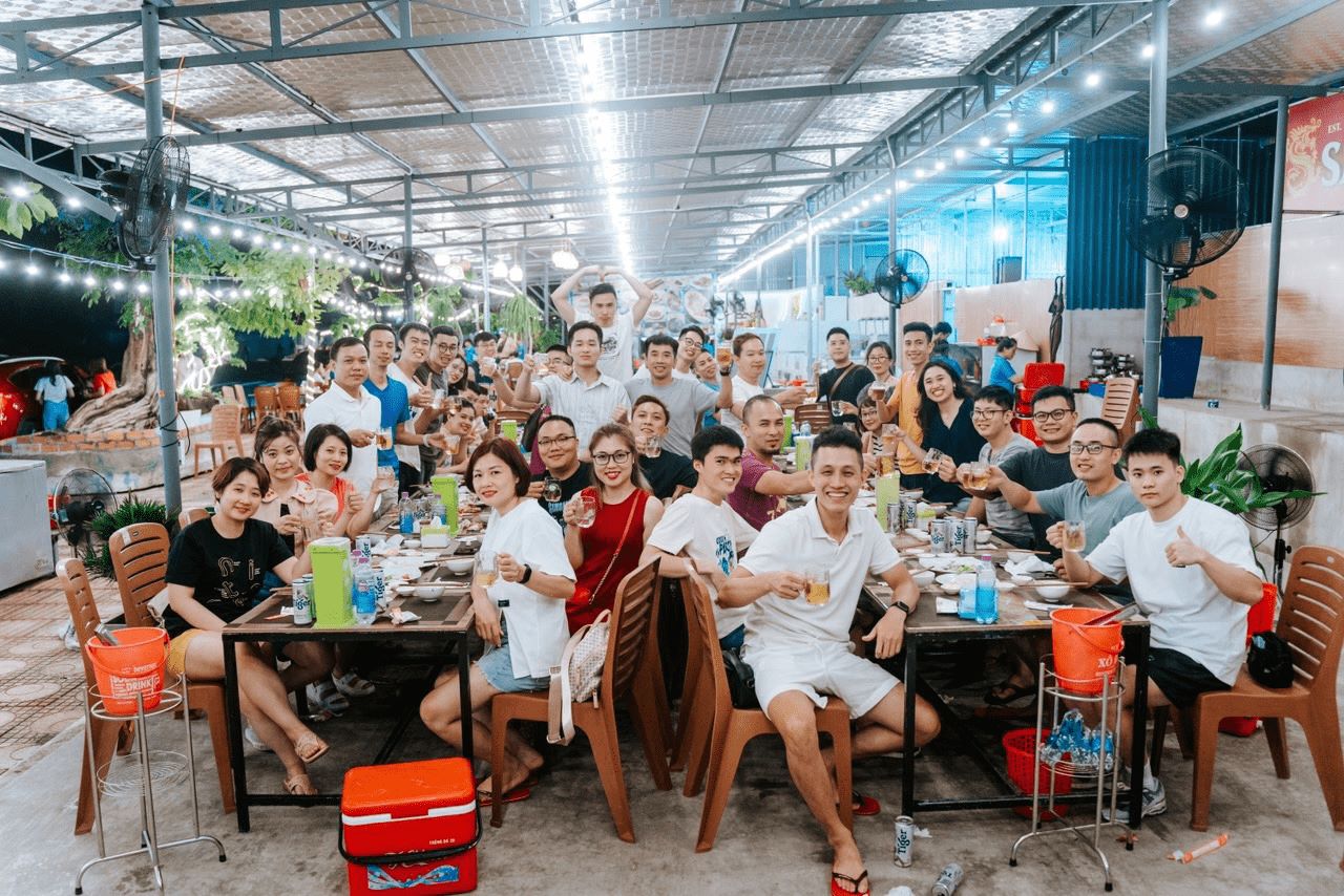 Large group enjoying outdoor team building dinner with drinks and smiles