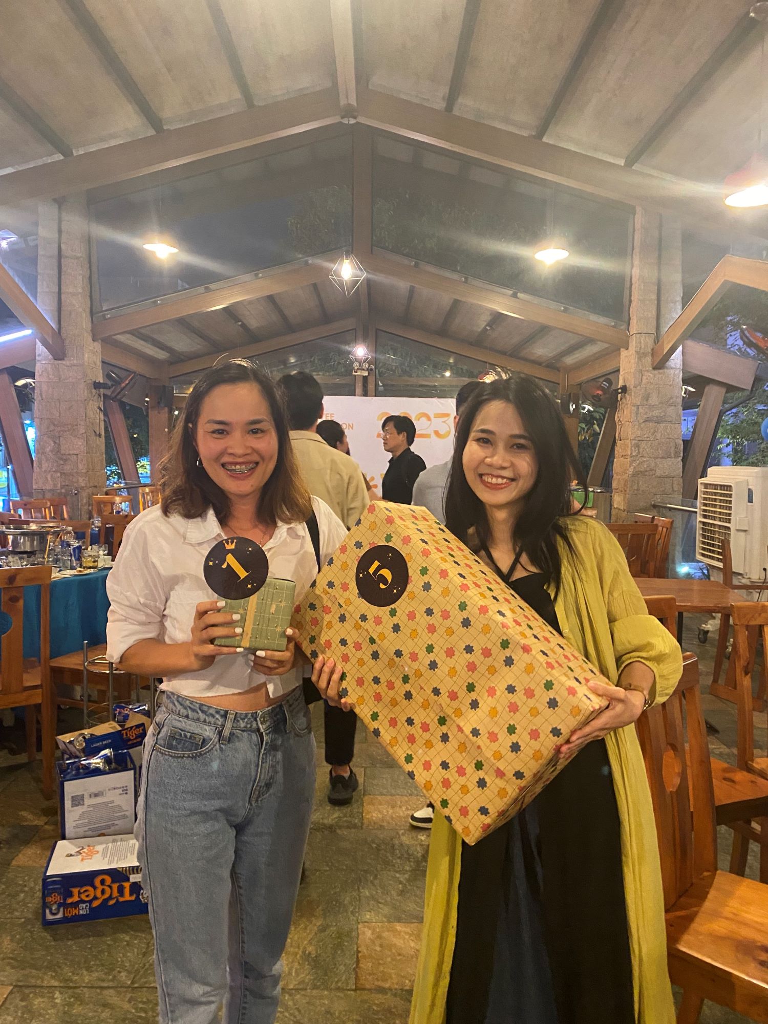 Two women smiling and holding numbered gifts at prize event celebration