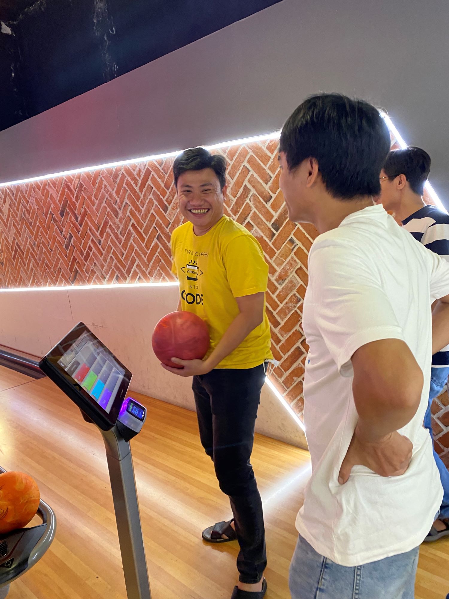 Friends enjoying bowling with a red ball and bright lane lighting