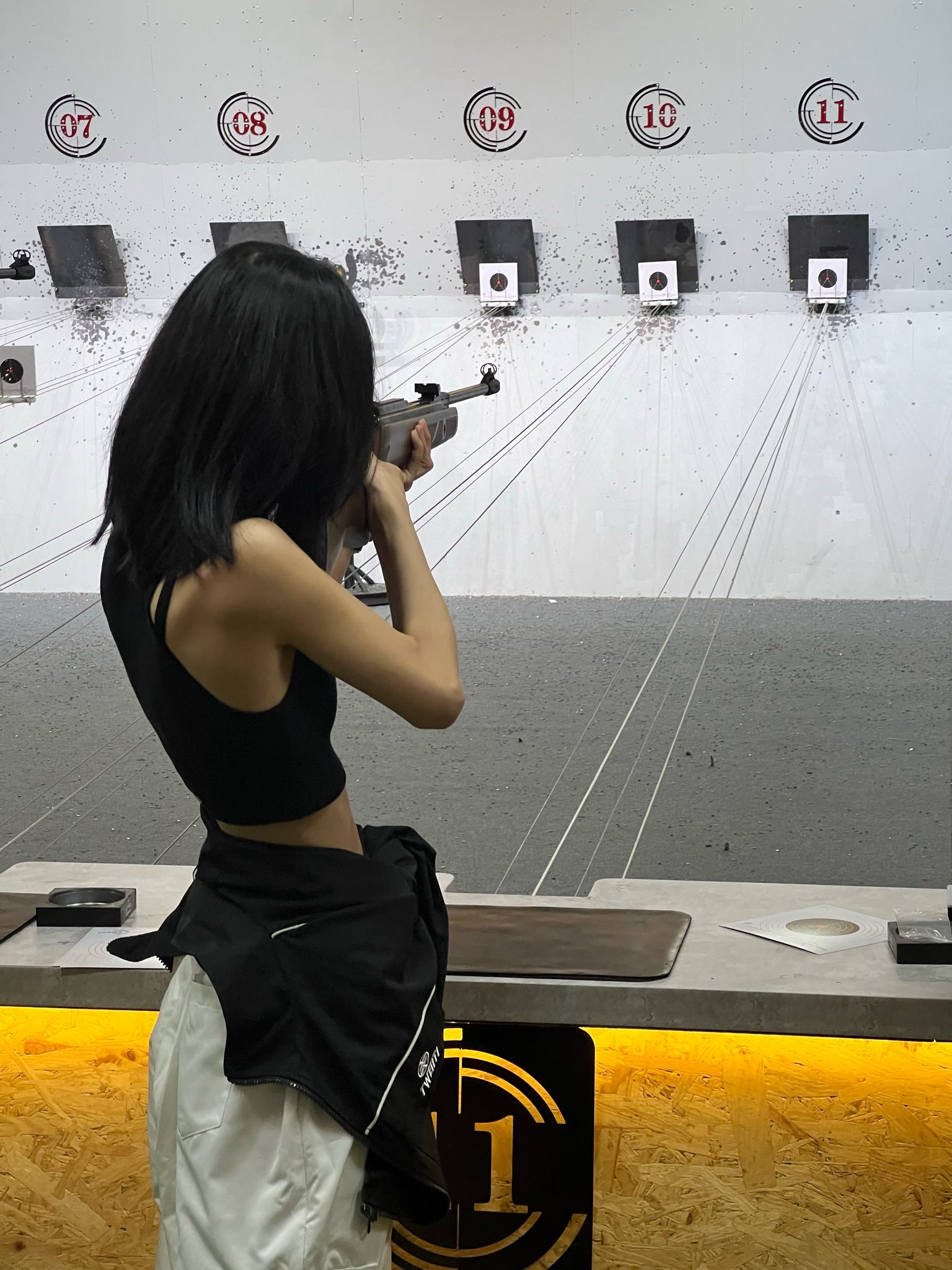 Woman aiming rifle at a shooting range with numbered targets from 7 to 11