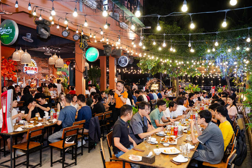 Busy outdoor restaurant with string lights and groups enjoying dinner together
