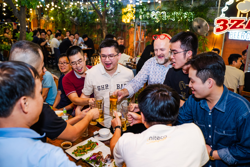 Friends clinking beer glasses celebrating at a lively outdoor party dinner