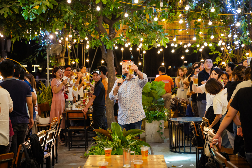 Outdoor party celebration with beer and string lights under tree canopy