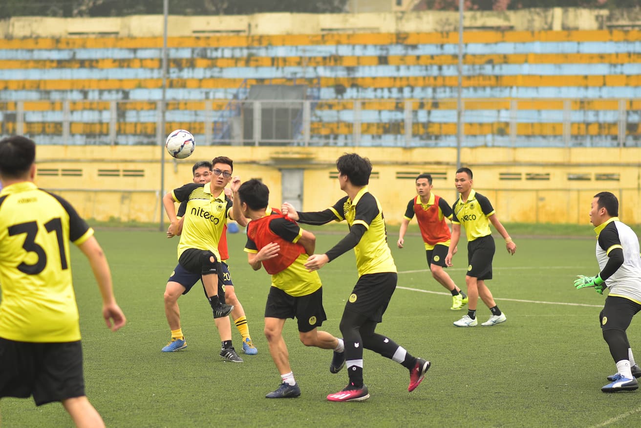 Active football players in yellow and red jerseys competing on a green field
