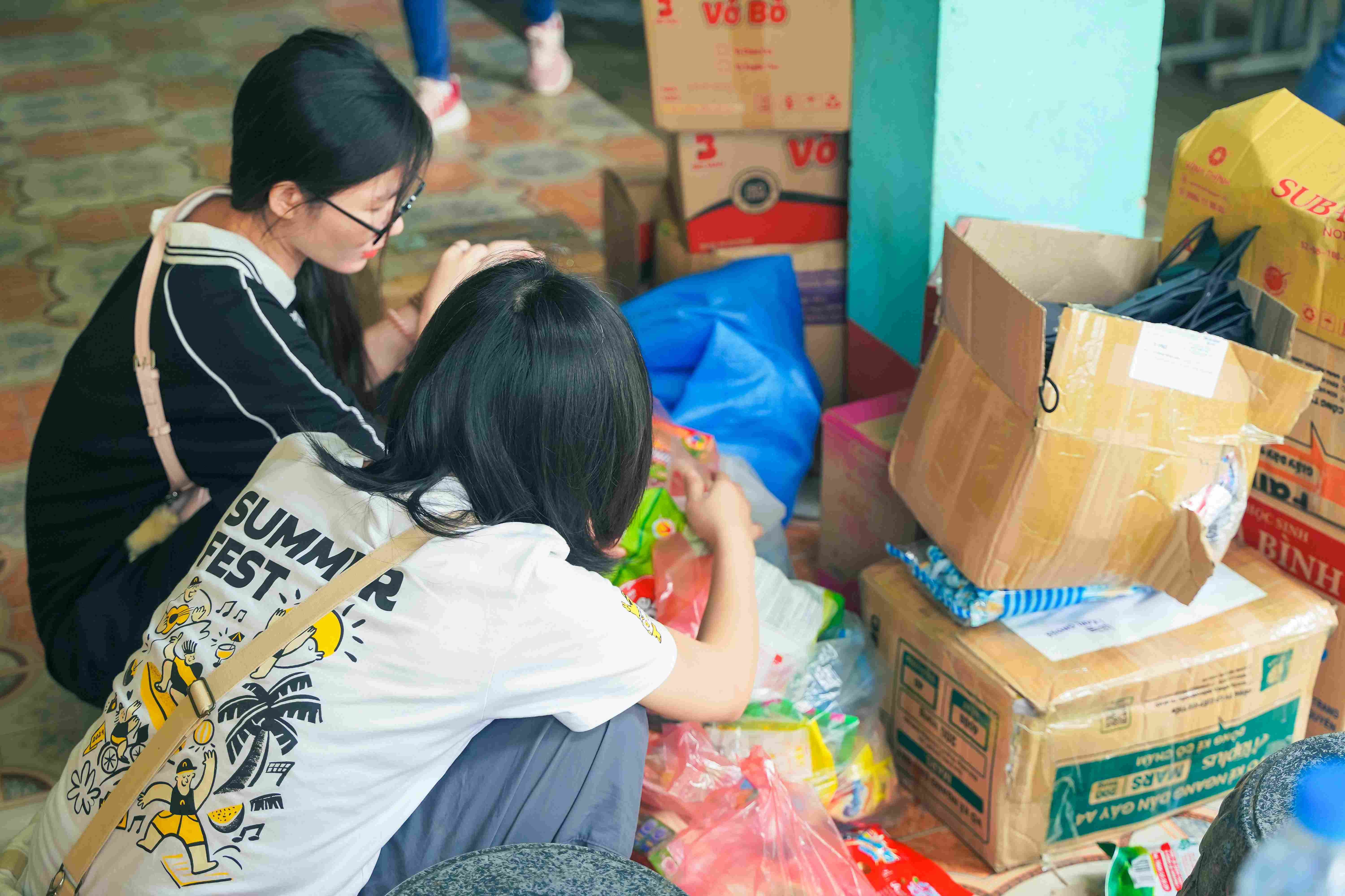 Two volunteers sorting donations near cardboard boxes and supplies