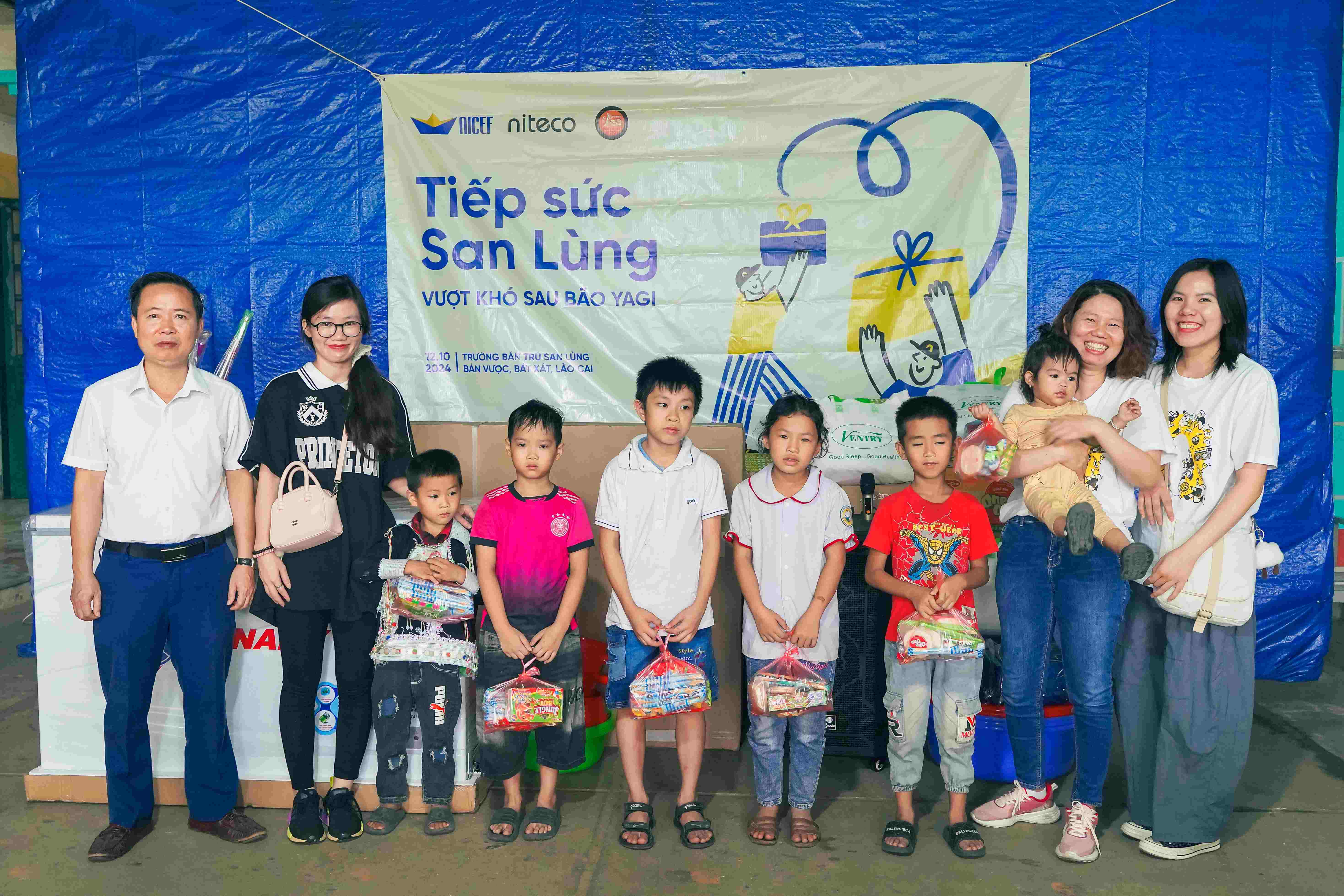 Children and volunteers holding gift bags at Tiếp sức San Lùng relief event