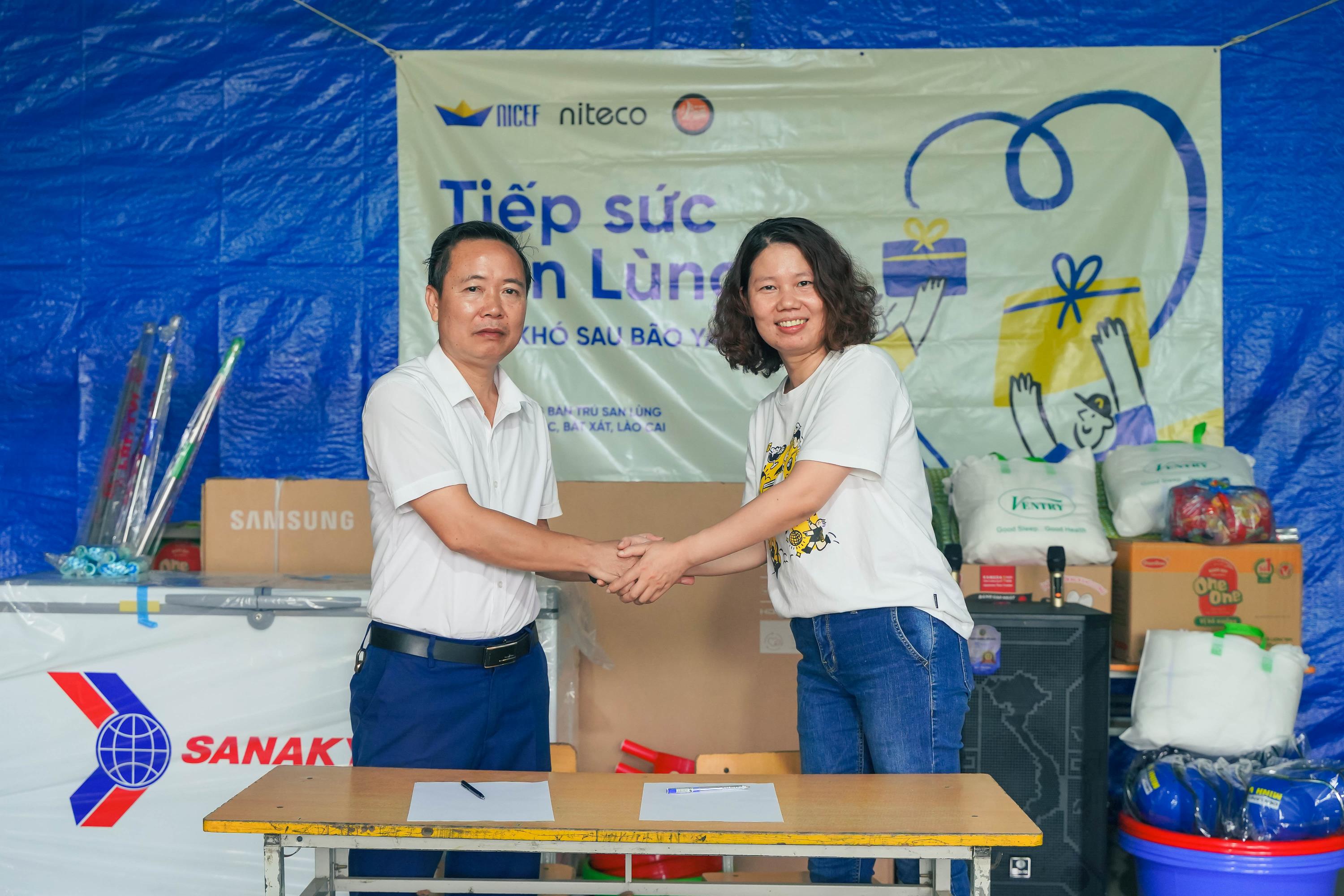 Two volunteers shaking hands during Tiếp Sức Mùa Lũ relief event with supplies