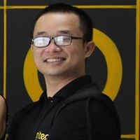 Smiling man wearing glasses and black hoodie with yellow logo background