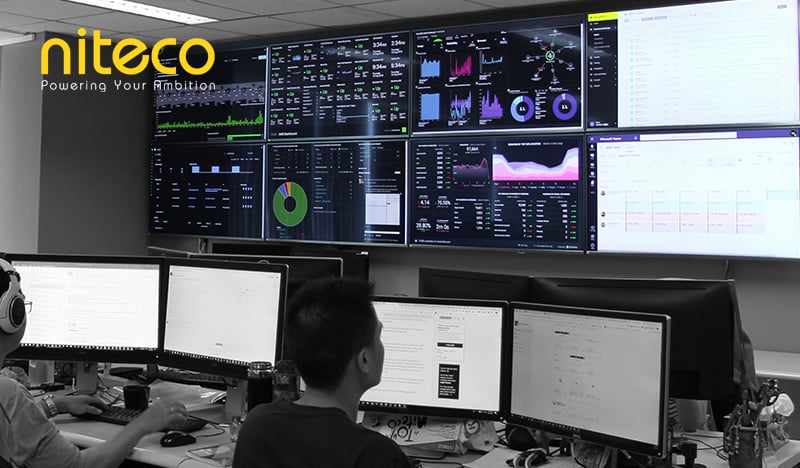Niteco team monitoring real-time data analytics on multiple large screens at office