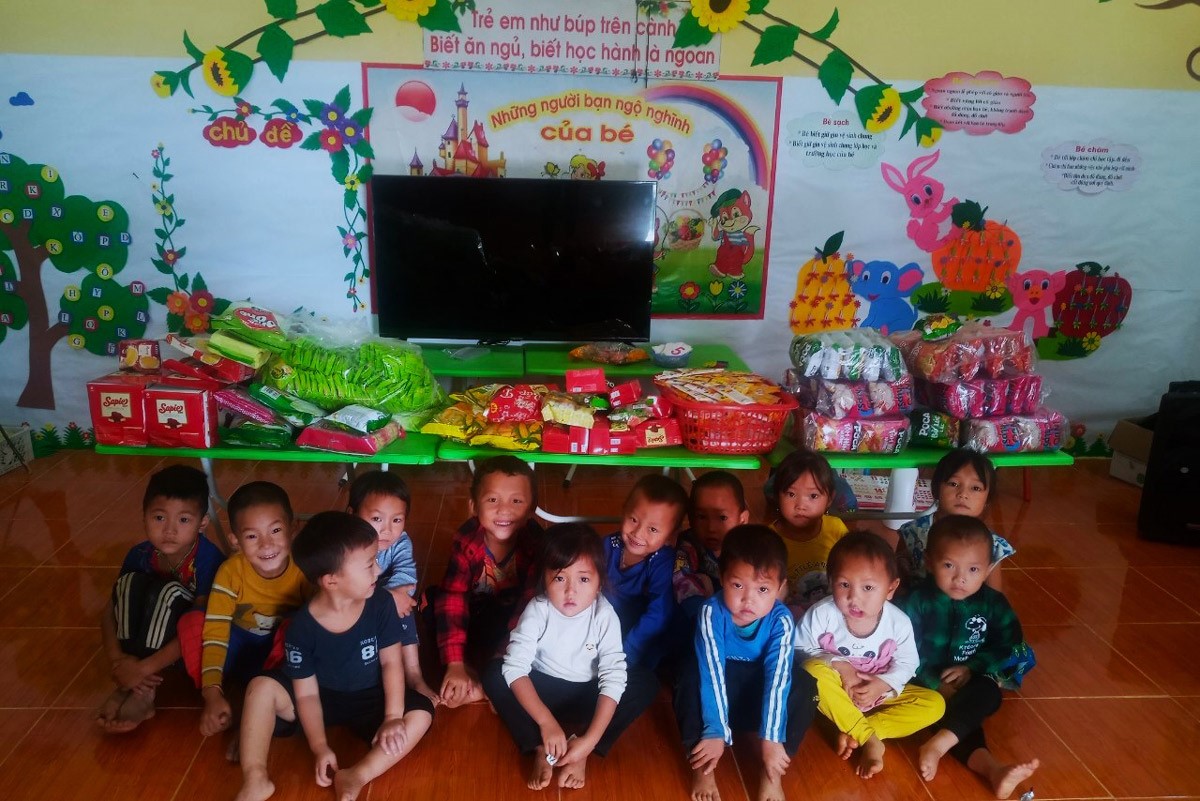 Children sitting on floor with school supplies and snacks in colorful classroom