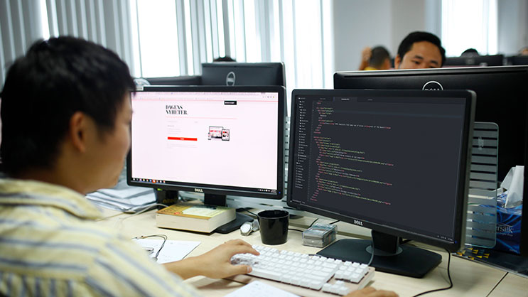 Developer working on responsive website design and coding at dual monitors