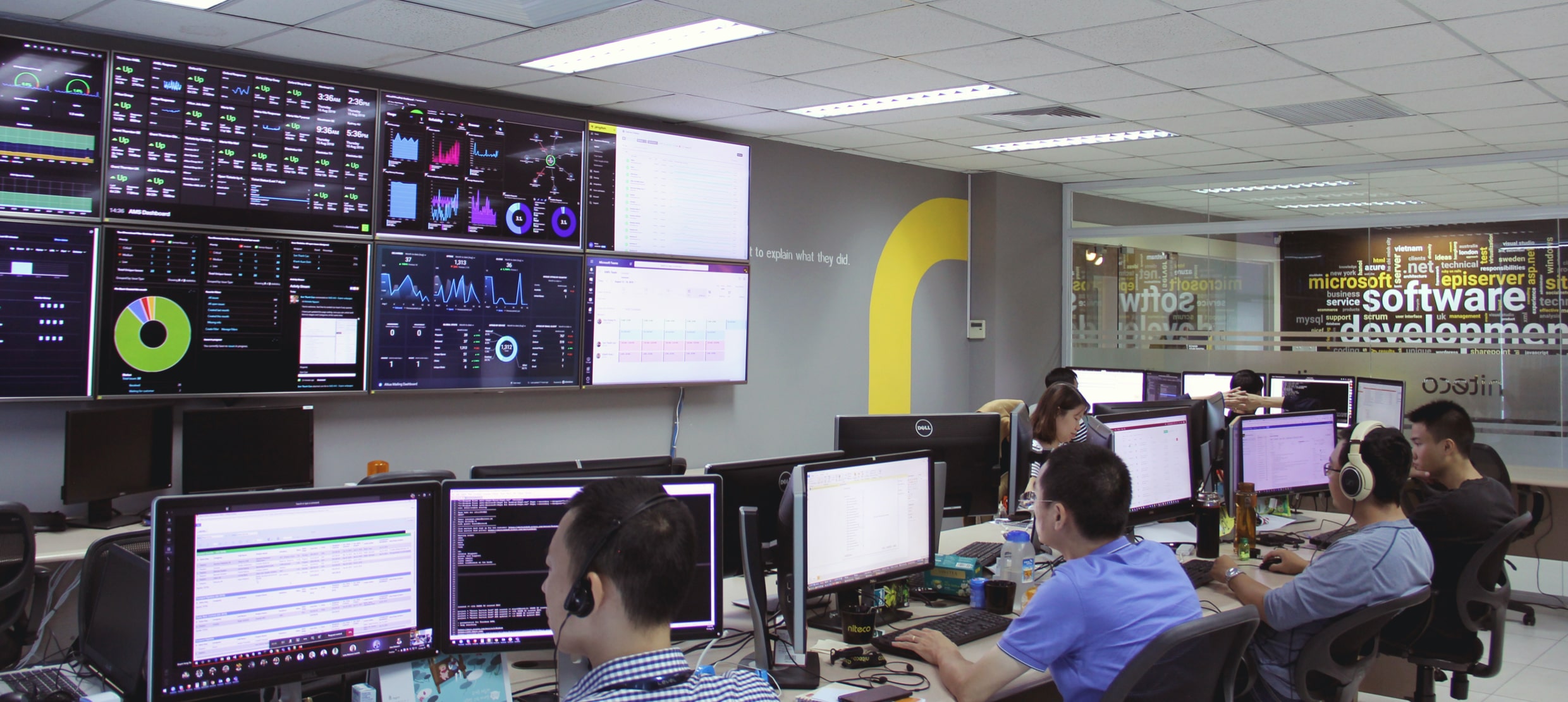 Software development team monitoring real-time data dashboards and coding
