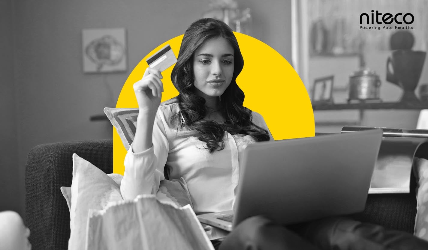 Woman holding credit card using laptop for online payment on couch