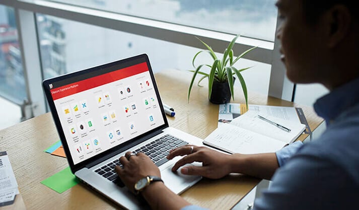 Person using laptop with desktop experience platform apps on screen at workspace