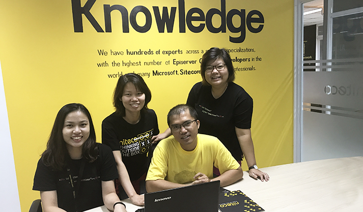 Team collaborating in front of a yellow Knowledge wall with Microsoft and Sitecore expertise keywords