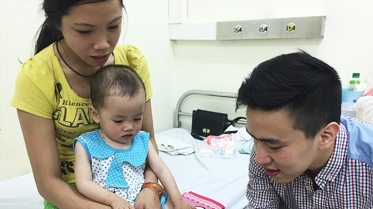 Mother and father caring for baby in pediatric hospital room setting