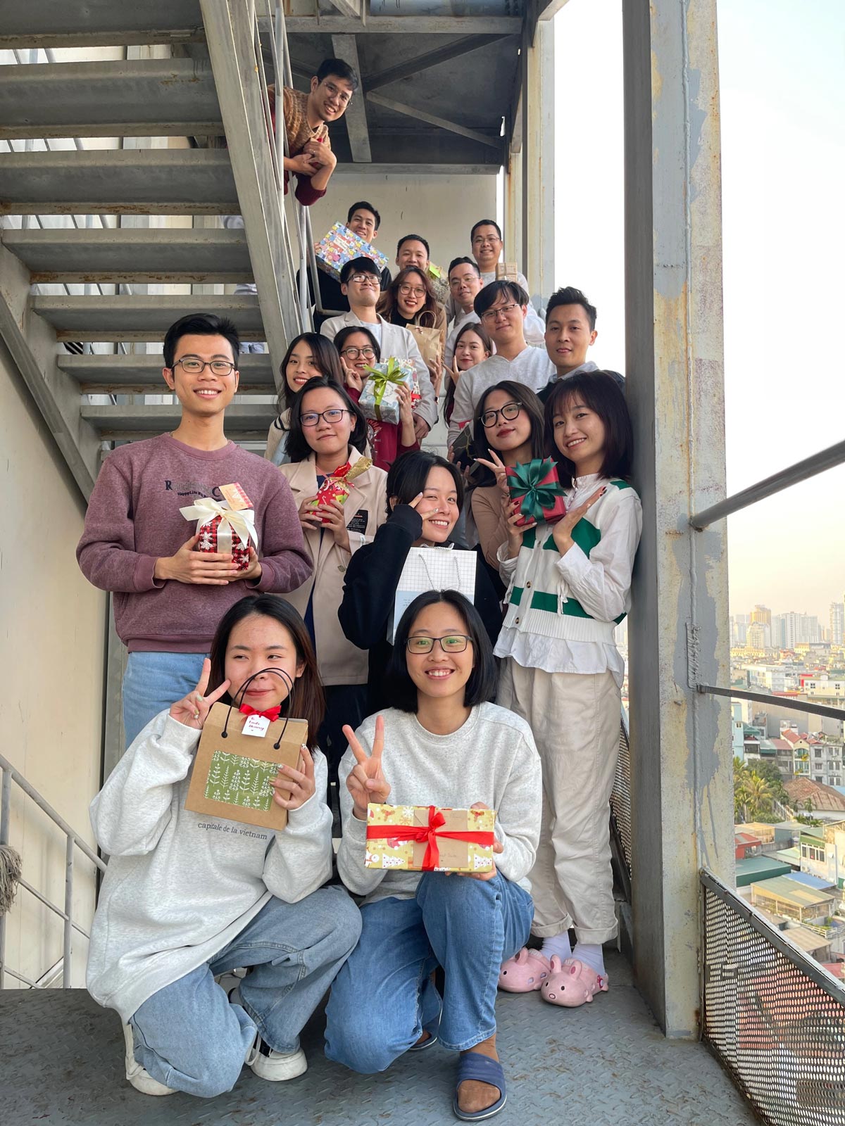 Group of friends on stairs holding wrapped presents and gift bags smiling