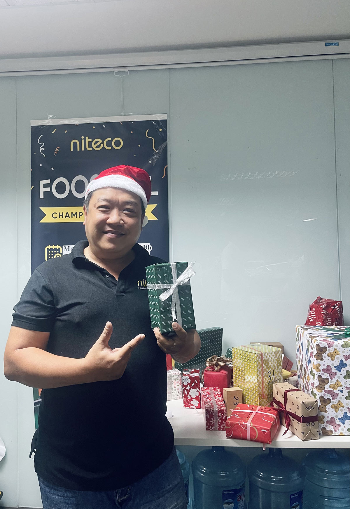 Man in Santa hat holding gift at Niteco Foodball Championship with presents