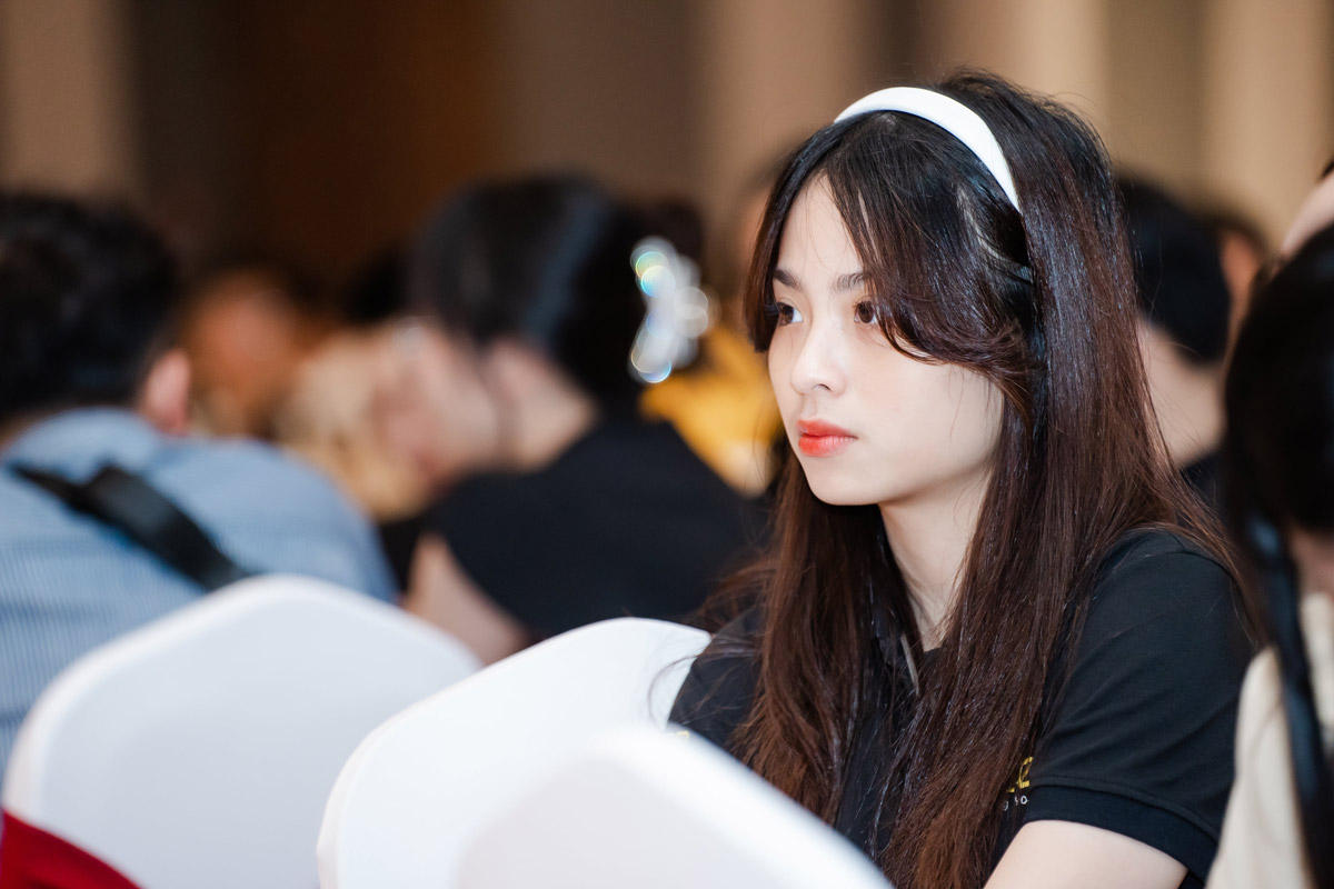 Young woman wearing white headband attentively listening at event conference