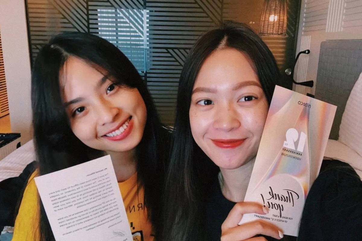 Two young women smiling holding thank you cards for anniversary event celebration