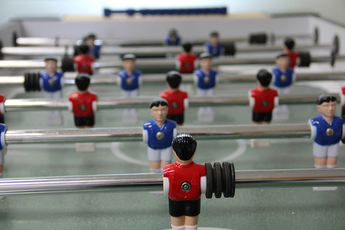 Foosball table players with blue and red uniforms on green field