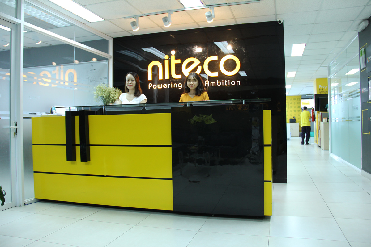 Niteco office reception with staff and yellow-black modern desk design