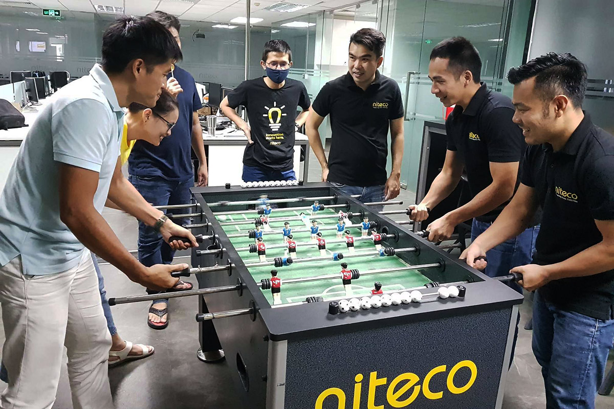 Employees playing foosball during a team-building activity at Niteco office