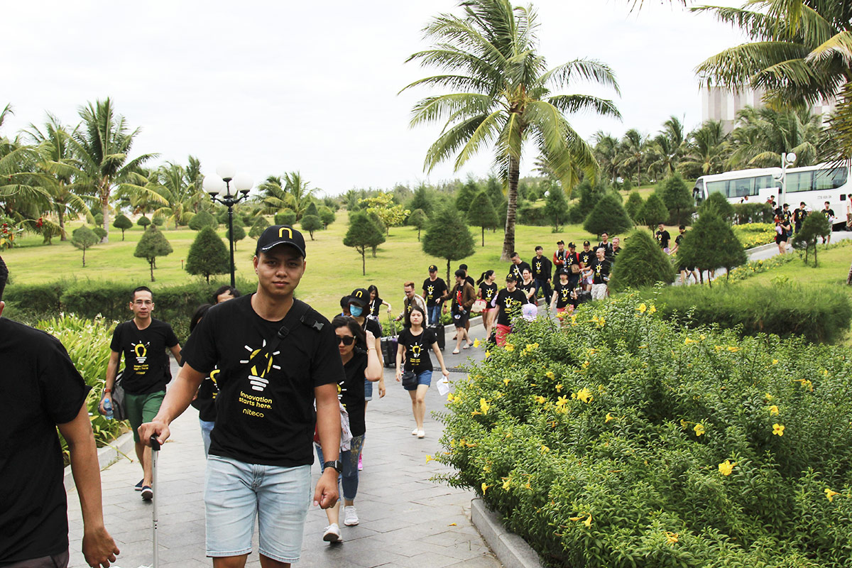 Team building event participants walking along a garden path under palm trees