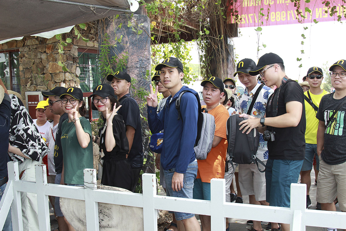 Group of tourists wearing black caps and backpacks waiting in line outdoors