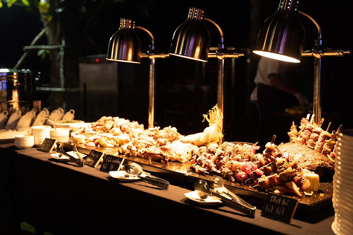 Buffet grill with skewers and roasted meats under warm lighting at night