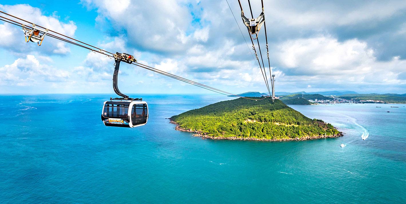 Cable car ride over turquoise ocean near lush green island and coastal town