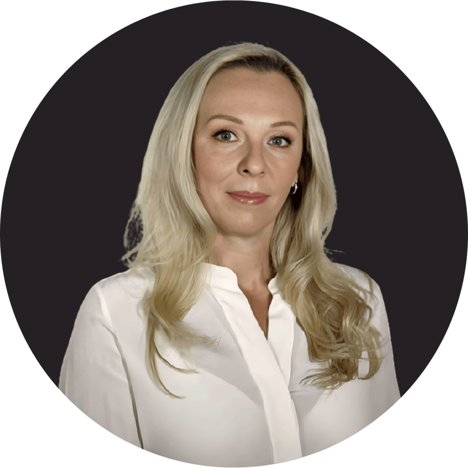 Woman with long blonde hair wearing a white blouse, dark background.