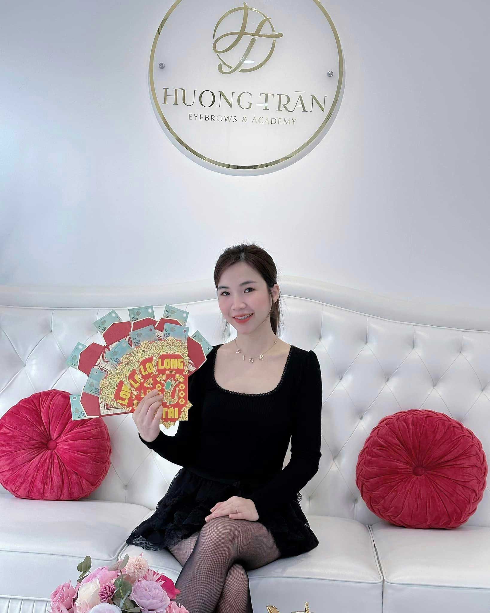 Young woman holding lucky money envelopes at Huong Tran Eyebrows & Academy