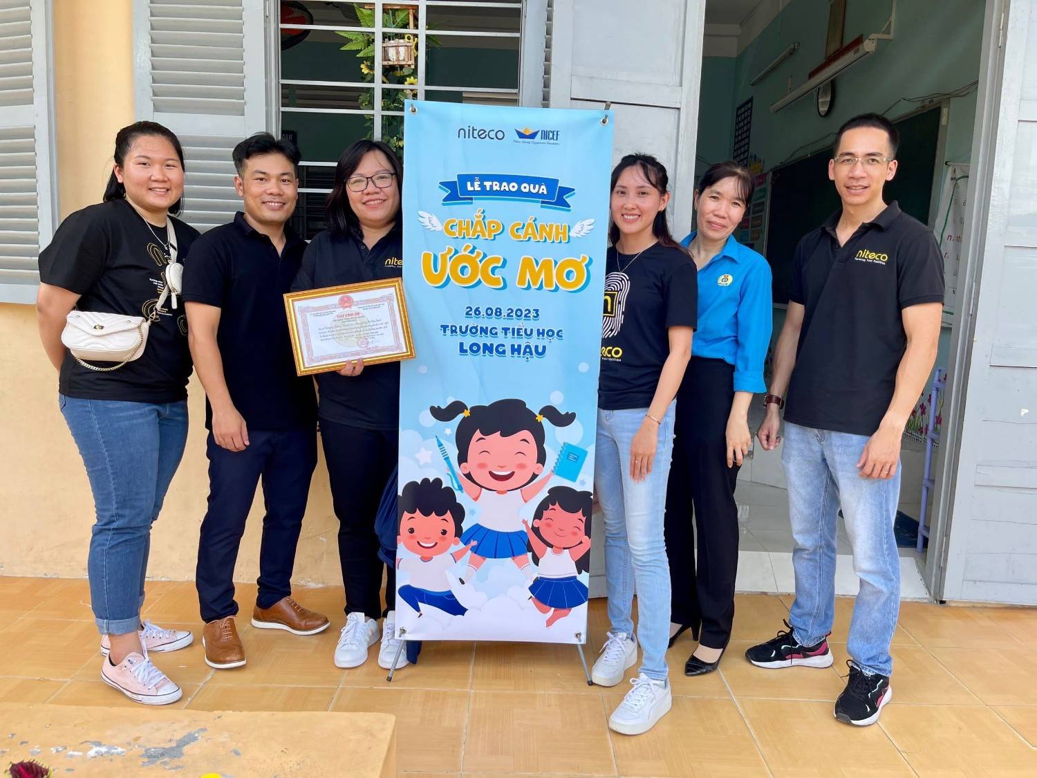 Niteco team at Long Hau Elementary School Dream Wings gift ceremony banner