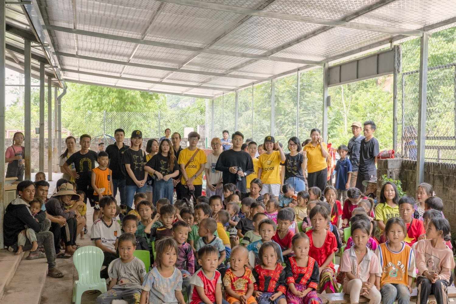 Children and volunteers gathered under a covered community space in rural area