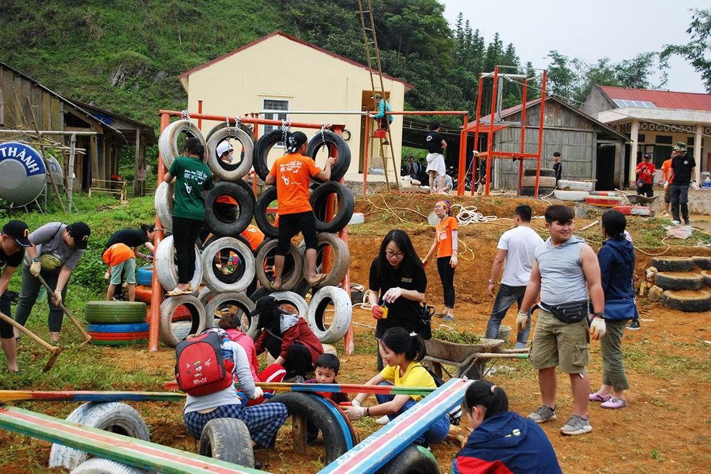 Community volunteers building an outdoor playground with recycled tires and wood