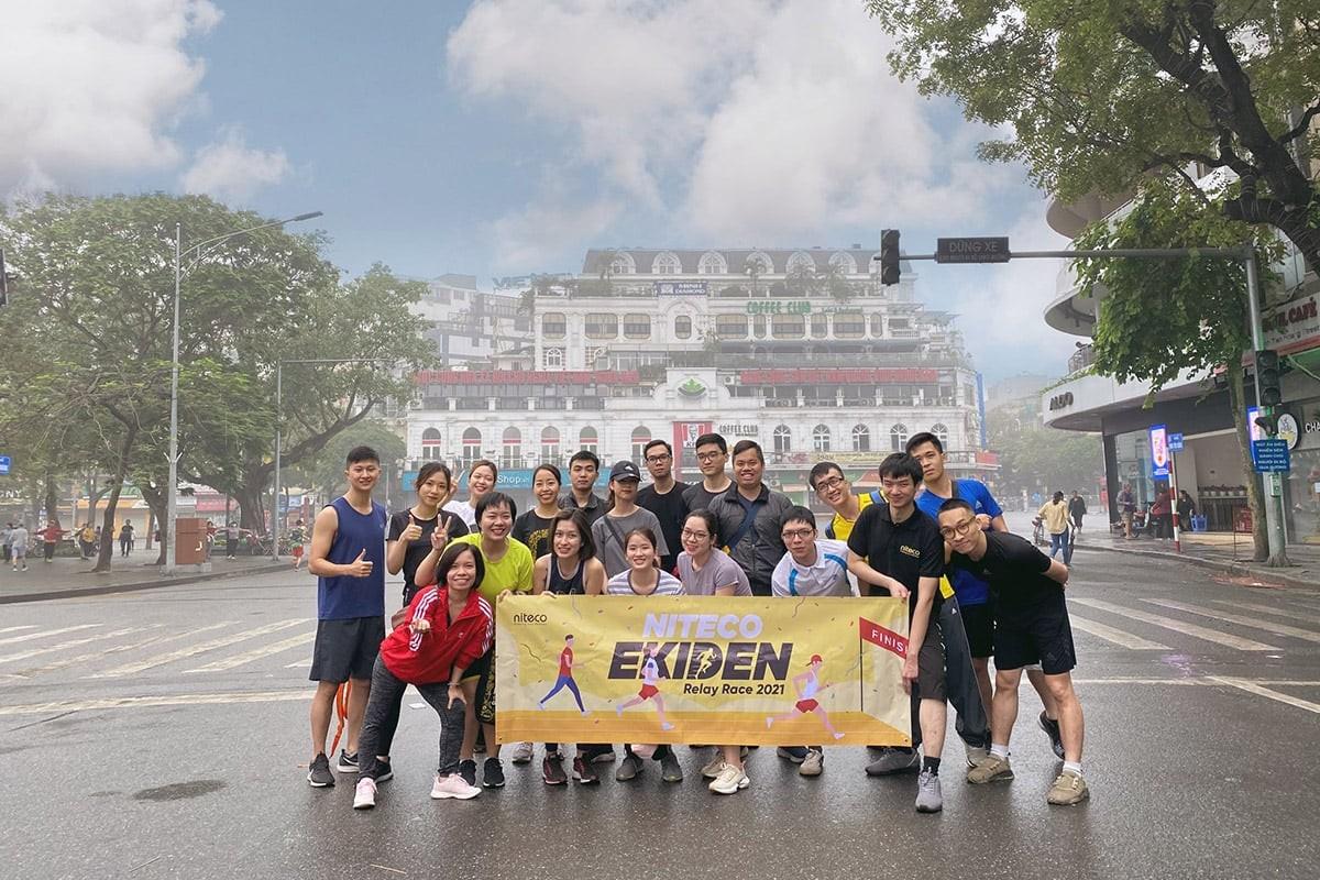 Group of runners holding Niteco Exiden Relay Race 2021 banner on city street