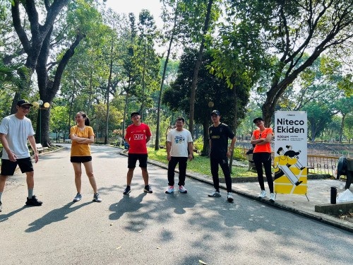Seven runners stand spaced apart on a shaded park path during the Niteco Ekiden event.