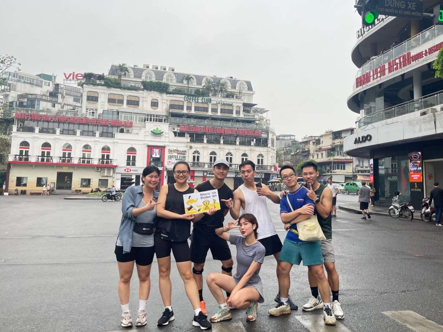 Group of runners posing with Hanoi 1930 Bistro and Coffee Club buildings in background