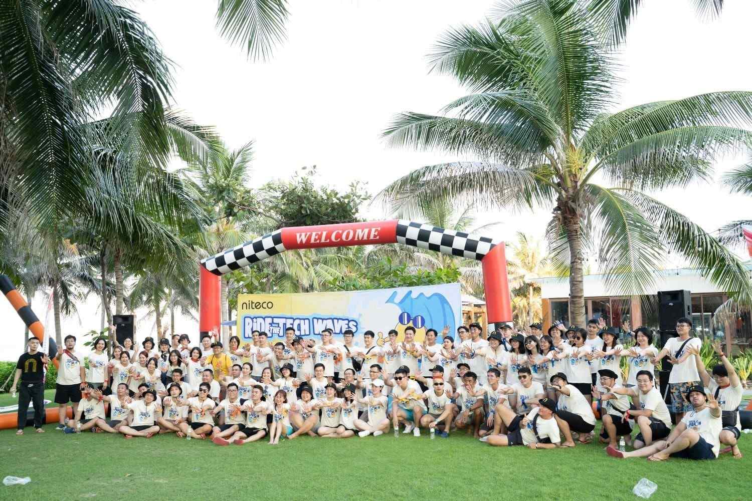 Team celebrating at Niteco Ride the Tech Waves event under palm trees