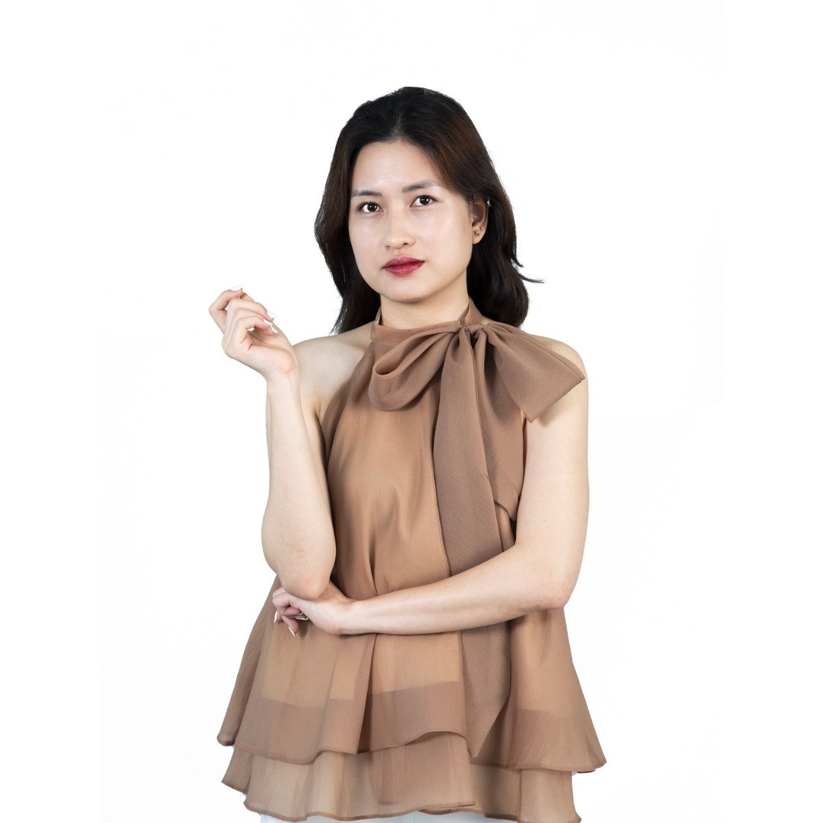 Young woman wearing a stylish brown sleeveless layered top with a bow neckline