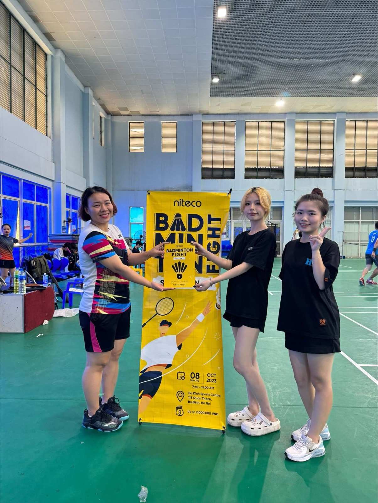 Three women holding a badminton fight first prize award at Ba Dinh Sports Centre