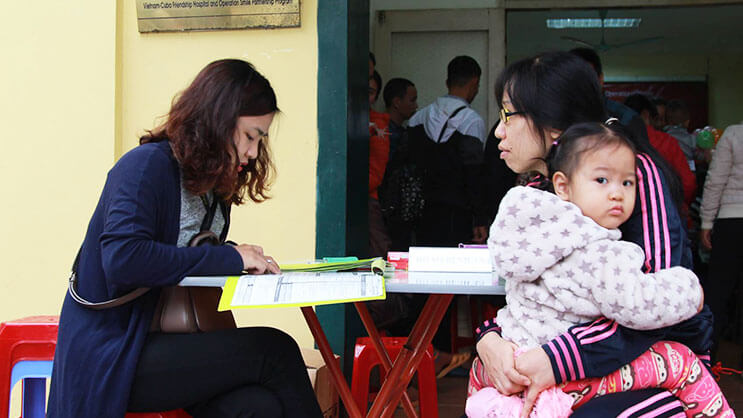 Mother holding child while registering for health care services at clinic